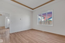 Wood-finish flooring, white walls, and a large window with white trim - 