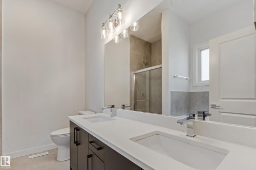 Dual vanity with white countertops, chrome fixtures, and dark wood-finish cabinetry - 32 Dalquist Bay, Leduc, AB 