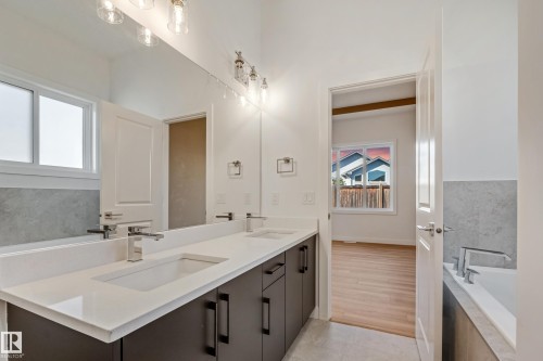 Dual vanity with undermount sinks, stone countertop, and dark cabinetry - 32 Dalquist Bay, Leduc, AB 