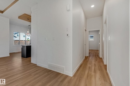 Wood-finish flooring throughout, recessed ceiling lighting, and a kitchen island with an undermount sink and pendant lighting - 32 Dalquist Bay, Leduc, AB 