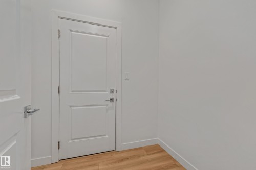 Two white paneled doors with chrome hardware, light wood-finish flooring, and white painted walls - 32 Dalquist Bay, Leduc, AB 