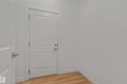 Two white paneled doors with chrome hardware, light wood-finish flooring, and white painted walls - 