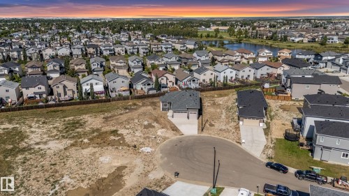 Cul-de-sac lot featuring undeveloped land, a paved driveway, and established neighborhood homes in the background - 32 Dalquist Bay, Leduc, AB 