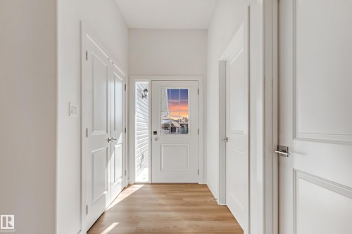Entryway featuring a paneled door with decorative glass, a sidelight, and wood-finish flooring - 32 Dalquist Bay, Leduc, AB 