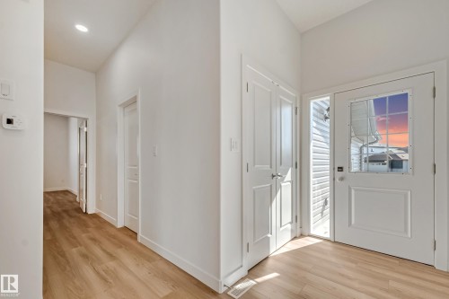 Entryway featuring wood-finish flooring, a paneled door with grid-patterned window, and a sidelight - 32 Dalquist Bay, Leduc, AB 
