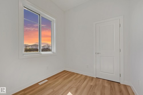 Wood-finish flooring, white walls, and a white interior door with a silver handle - 32 Dalquist Bay, Leduc, AB 