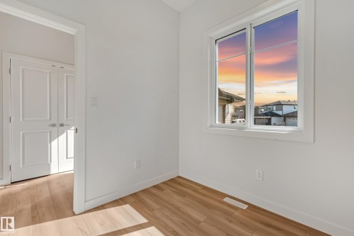 Bright room featuring wood-finish flooring, white walls, and a large window with white trim - 32 Dalquist Bay, Leduc, AB 