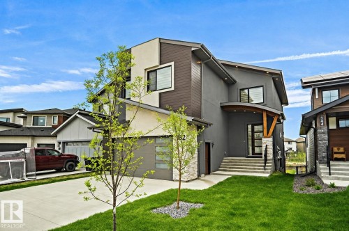 Modern architectural design featuring varied facade materials, a stone-clad entry, and a covered porch - 162 Edgewater Circle, Leduc, AB 