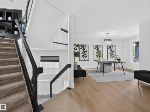 Open concept living area with wood-finish flooring and a contemporary chandelier - #59 10550 Ellerslie Rd Sw, Edmonton, AB - Indoor With Fireplace