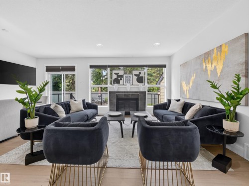 Living area featuring light wood-finish flooring, recessed lighting, and a contemporary fireplace with a dark tile surround - #59 10550 Ellerslie Rd Sw, Edmonton, AB - Indoor Photo Showing Living Room