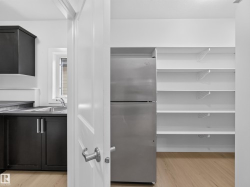 Bright kitchen area featuring dark cabinetry with brushed nickel hardware and a stainless steel sink - #59 10550 Ellerslie Rd Sw, Edmonton, AB - Indoor Photo Showing Other Room