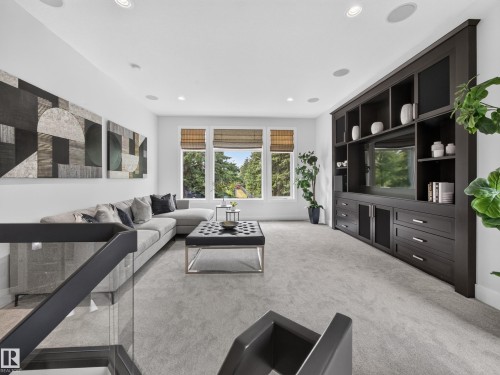 Spacious upper-level room featuring a built-in media center with ample storage, large windows, recessed lighting, and carpet flooring - #59 10550 Ellerslie Rd Sw, Edmonton, AB - Indoor Photo Showing Living Room