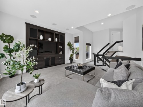 Spacious entertainment area featuring a built-in media cabinet, recessed lighting, and grey carpeting - #59 10550 Ellerslie Rd Sw, Edmonton, AB - Indoor