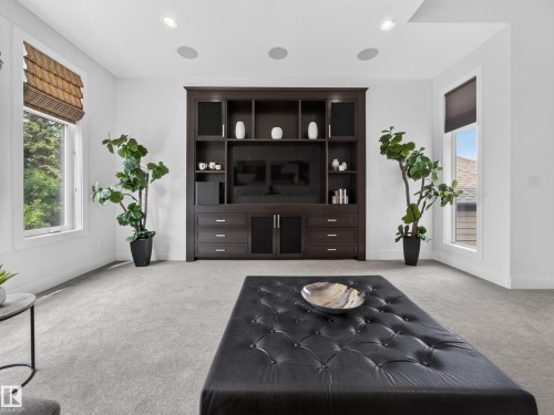 Built-in media center with ample storage, recessed ceiling lighting, two large windows with blinds, and light-toned carpeting - #59 10550 Ellerslie Rd Sw, Edmonton, AB - Indoor
