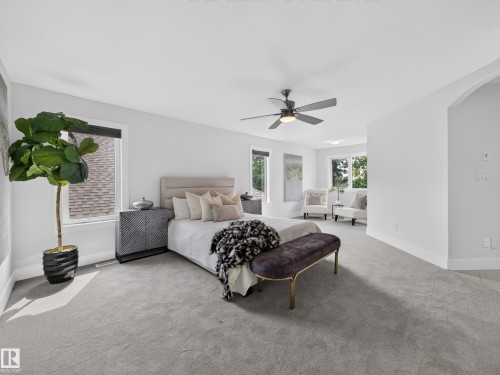 Spacious bedroom with light gray carpeting, multiple windows, and a ceiling fan - #59 10550 Ellerslie Rd Sw, Edmonton, AB - Indoor Photo Showing Bedroom