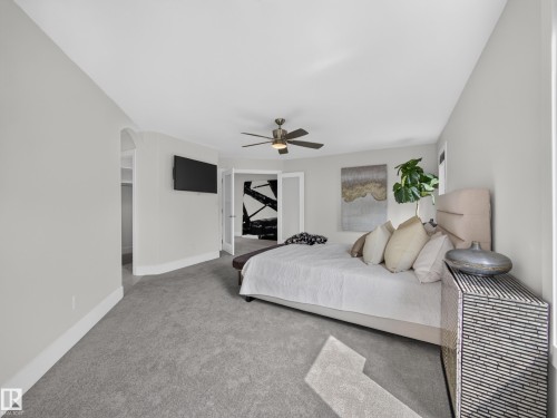 Carpeted room featuring a ceiling fan, light gray walls, and French doors - #59 10550 Ellerslie Rd Sw, Edmonton, AB - Indoor Photo Showing Bedroom