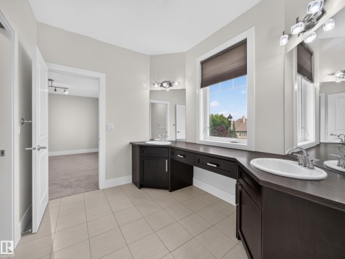 Dual vanity with dark wood-finish cabinetry, integrated sinks, and chrome fixtures - #59 10550 Ellerslie Rd Sw, Edmonton, AB - Indoor Photo Showing Bathroom