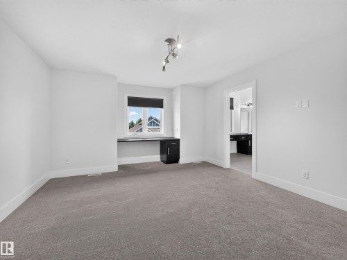 Neutral tone carpeting complementing crisp white walls and baseboards - #59 10550 Ellerslie Rd Sw, Edmonton, AB - Indoor Photo Showing Other Room