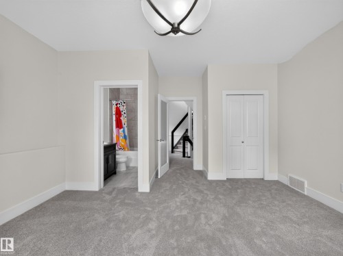 Carpeted upper-level space featuring a contemporary ceiling light fixture, white baseboards, and a bi-fold closet door - #59 10550 Ellerslie Rd Sw, Edmonton, AB - Indoor Photo Showing Other Room