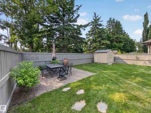 Spacious backyard featuring a paver patio area, green lawn, and a storage shed - #59 10550 Ellerslie Rd Sw, Edmonton, AB - Outdoor With Backyard