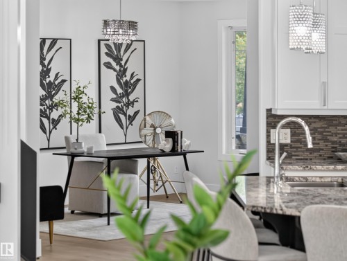 Modern interior showcasing a contemporary chandelier, large windows with white trim, and light wood-finish flooring - #59 10550 Ellerslie Rd Sw, Edmonton, AB - Indoor