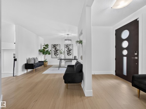 Modern entry door with circular and rectangular lites, complemented by light wood-finish flooring - #59 10550 Ellerslie Rd Sw, Edmonton, AB - Indoor