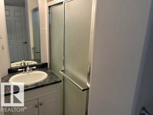 White vanity with base cabinetry, dark countertop, and integrated white sink - #407 11103 84 Av Nw, Edmonton, AB 