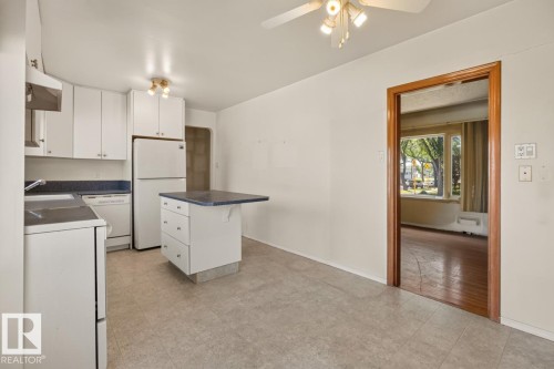 Kitchen featuring white cabinetry, a freestanding refrigerator, a built-in dishwasher, and a center island with countertop - 12309 128 Street Nw, Edmonton, AB 