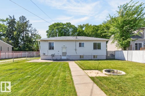 Expansive lawn featuring a concrete pathway, a built-in fire pit, and a chain-link fence - 12309 128 Street Nw, Edmonton, AB 