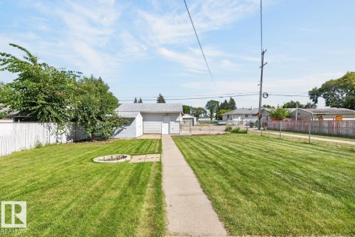 Expansive grassy yard with a concrete pathway leading to a detached garage - 12309 128 Street Nw, Edmonton, AB 