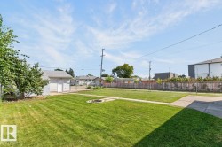 Expansive green lawn with a built-in fire pit, concrete pathways, and a detached garage with a shingled roof - 