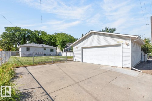 Detached garage with white siding and a panel garage door, featuring exterior wall lanterns - 12309 128 Street Nw, Edmonton, AB 