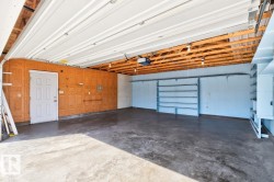 Concrete flooring, exposed wood beam ceiling, built-in shelving, white overhead garage door, built-in storage cabinets - 