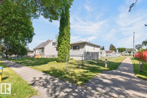 Expansive green lawn with mature trees, concrete sidewalks, and chain-link fencing - 12309 128 Street Nw, Edmonton, AB 