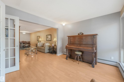 Light wood-finish flooring throughout, framed doorway, and white French doors - #203 10171 119 St Nw, Edmonton, AB 