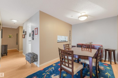Open concept dining space with wood-finish flooring, recessed lighting, and a pass-through window - #203 10171 119 St Nw, Edmonton, AB 
