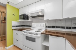Kitchen featuring white cabinetry, brown countertops, and a white tile backsplash with a black accent strip - 
