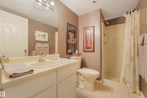 Single vanity with an integrated sink and brushed nickel faucet, a toilet, and a stand-up shower with a shower curtain - #203 10171 119 St Nw, Edmonton, AB 