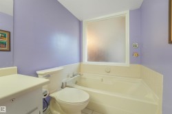 Built-in bathtub with white perimeter tiling and a frosted window - 