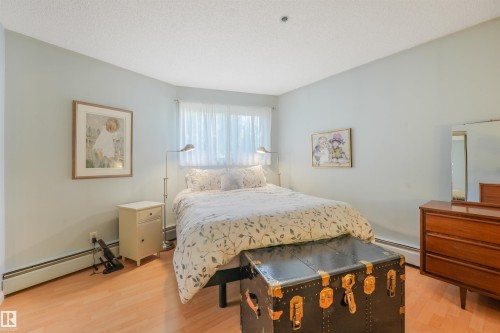 Wood-finish flooring, light-toned walls, and a window with sheer curtains - #203 10171 119 St Nw, Edmonton, AB 