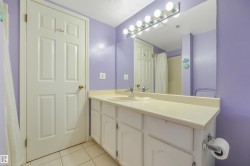 Vanity with integrated sink, white cabinetry, and an expansive wall mirror - 