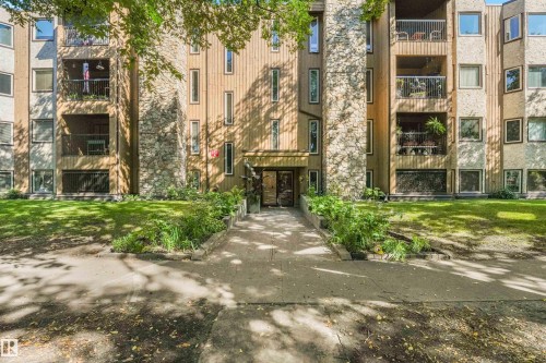 Building exterior featuring wood siding, stone accents, multiple balconies with metal railings, and a central entrance - #203 10171 119 St Nw, Edmonton, AB 
