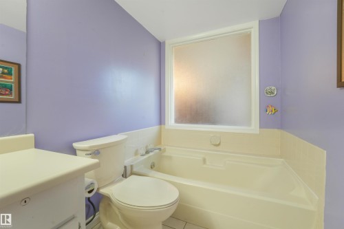 Built-in bathtub with white perimeter tiling and a frosted window - #203 10171 119 St Nw, Edmonton, AB 