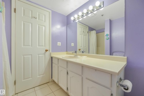 Vanity with integrated sink, white cabinetry, and an expansive wall mirror - #203 10171 119 St Nw, Edmonton, AB 