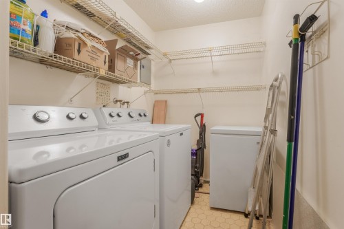 Dedicated laundry area featuring wire shelving, a washer, and a dryer - #203 10171 119 St Nw, Edmonton, AB 