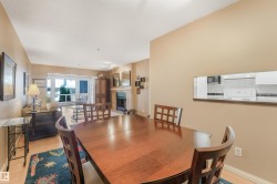 Open-concept living area with wood-finish flooring, a pass-through window, and a built-in fireplace featuring a stone surround - 