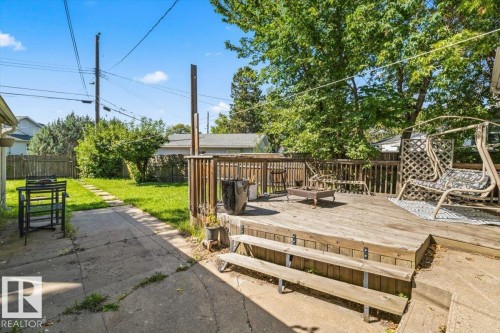 Expansive backyard featuring a multi-level wooden deck with lattice railing, a concrete patio, and a grass lawn with a stone path - 10990 135 Street Nw, Edmonton, AB 
