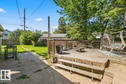 Expansive backyard featuring a multi-level wooden deck with lattice railing, a concrete patio, and a grass lawn with a stone path - 