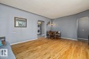 Hardwood flooring, arched doorways, window with natural light, wall-mounted light fixture, and a stacked washer and dryer - 10990 135 Street Nw, Edmonton, AB 