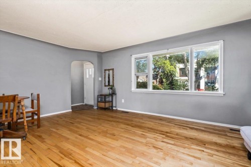 Hardwood flooring, painted walls, large window, and arched doorway - 10990 135 Street Nw, Edmonton, AB 